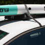 Closeup of a paddle board strapped down to the Quick Strap Board Rack on top of a sedan