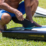 Man inserting a center fin into the center fin slot on his Rackham paddle board
